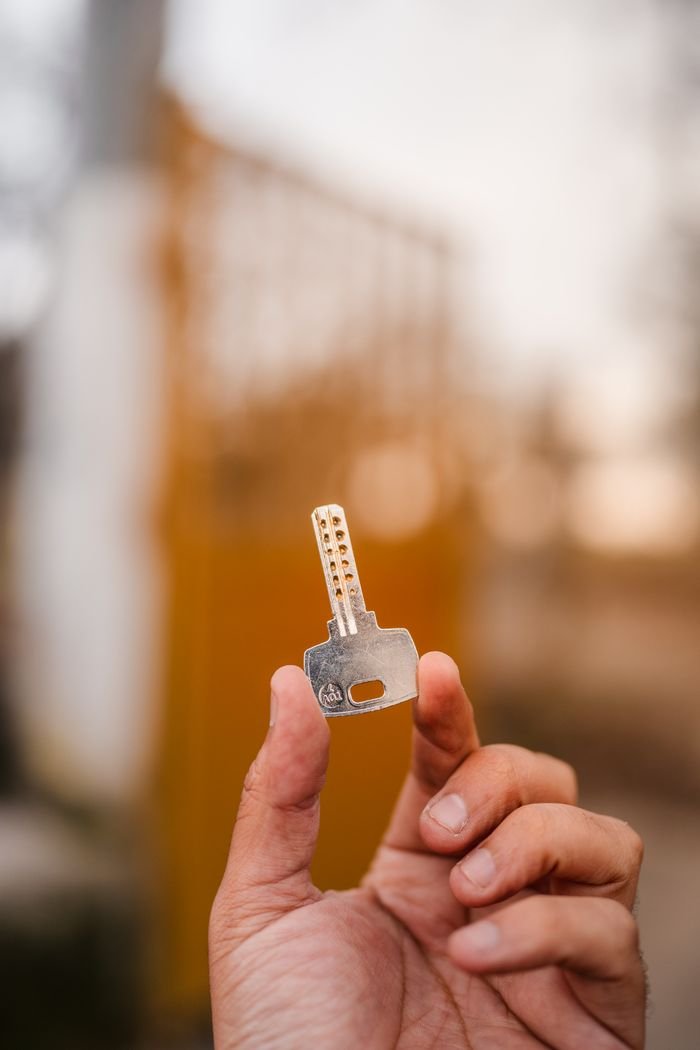 A detailed close-up of a hand holding a security key, with a blurred outdoor background.